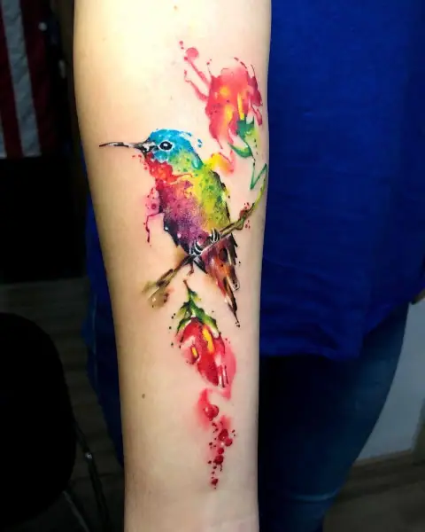 Vibrant watercolor hummingbird on branch tattoo by Neto, Boca Raton