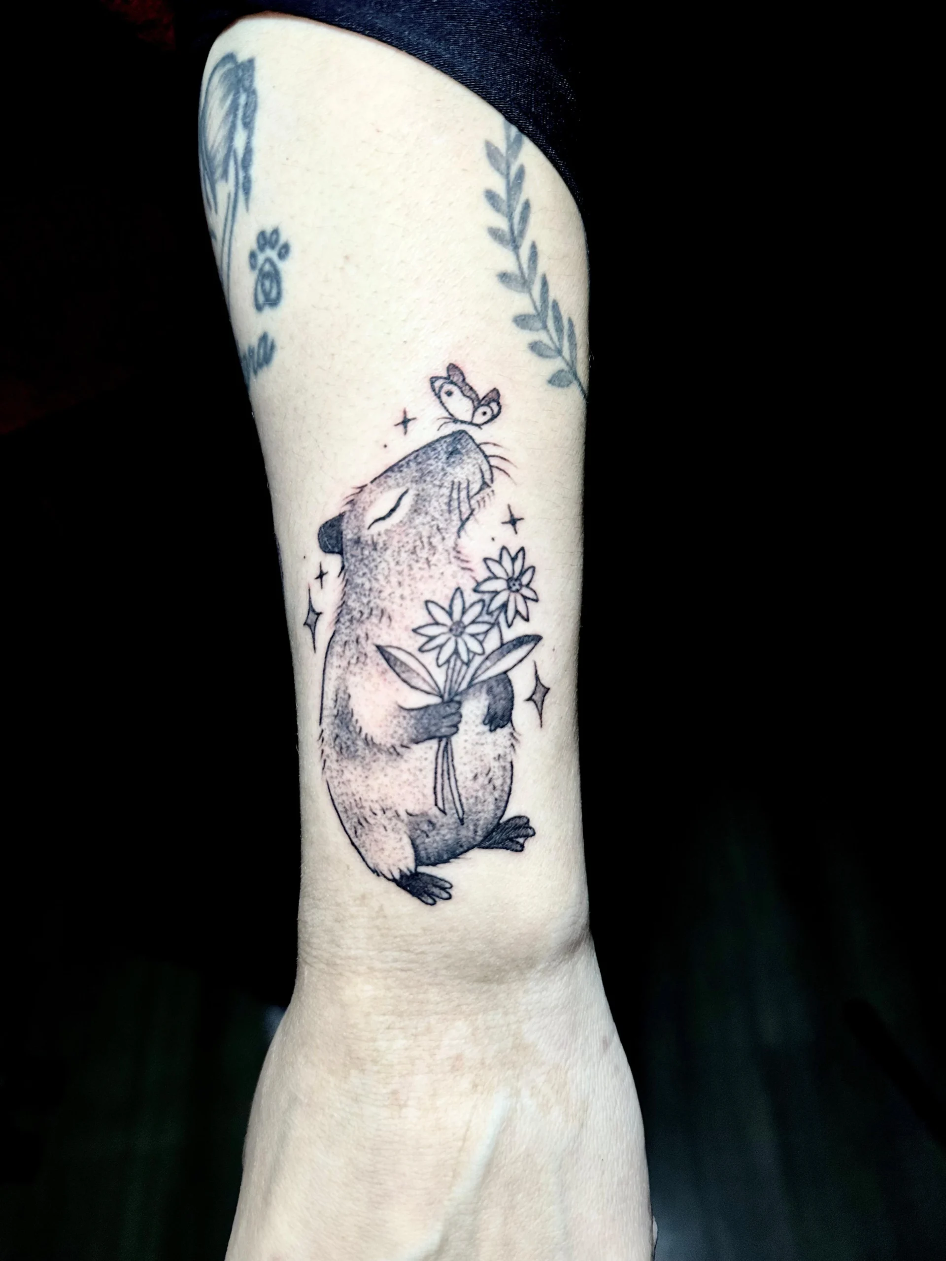 Cute capybara tattoo holding flowers sketch style wrist ink Boca Raton artist
