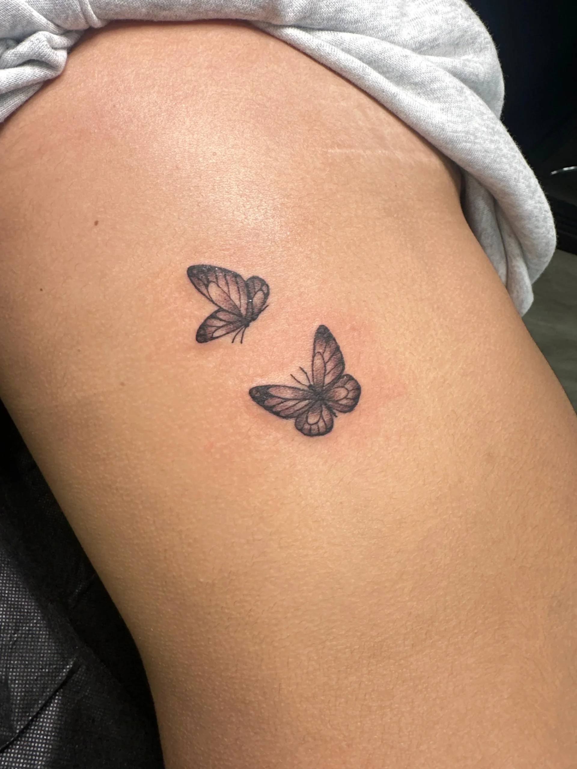Two small butterflies tattoo fine line hip placement minimalist ink Boca Raton