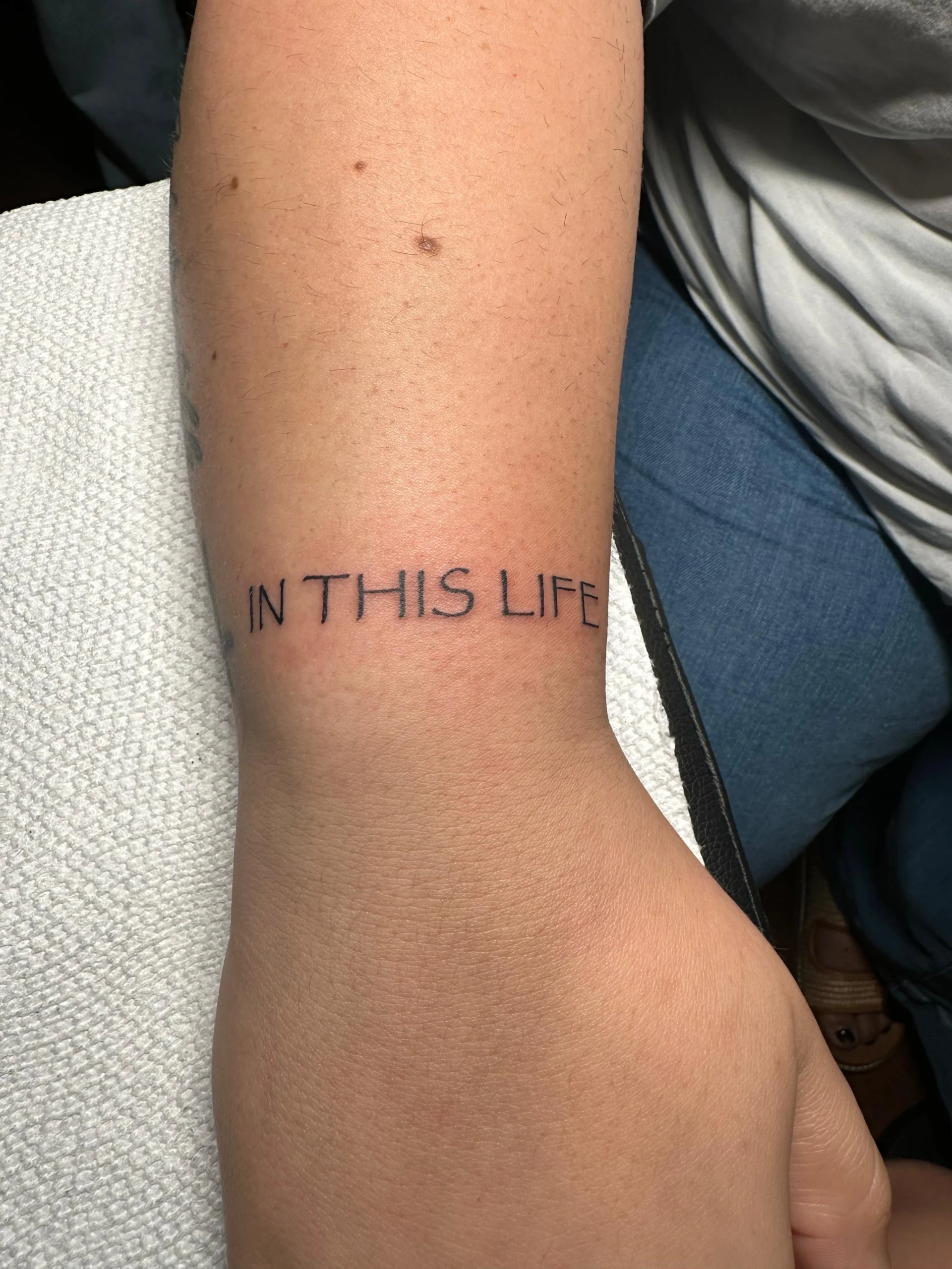 Minimalist typewriter font quote tattoo IN THIS LIFE wrist ink Boca Raton