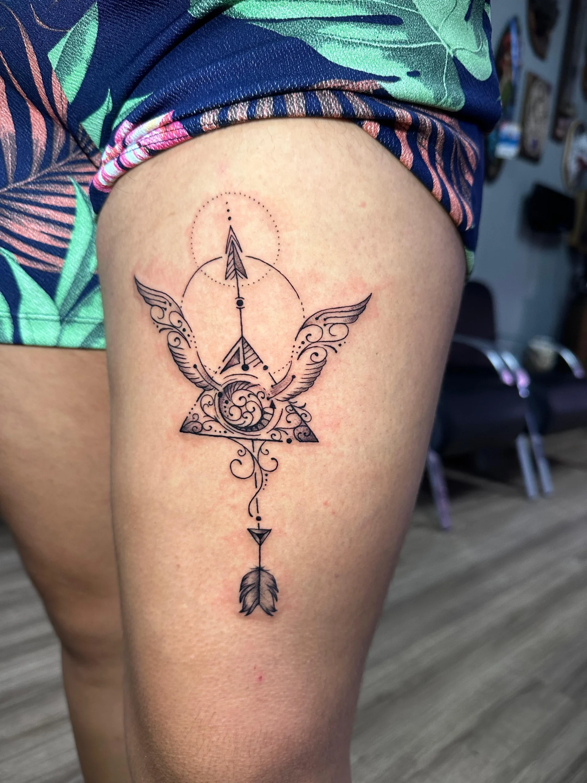 Ornamental arrow and wings tattoo on thigh fine line filigree Boca Raton studio