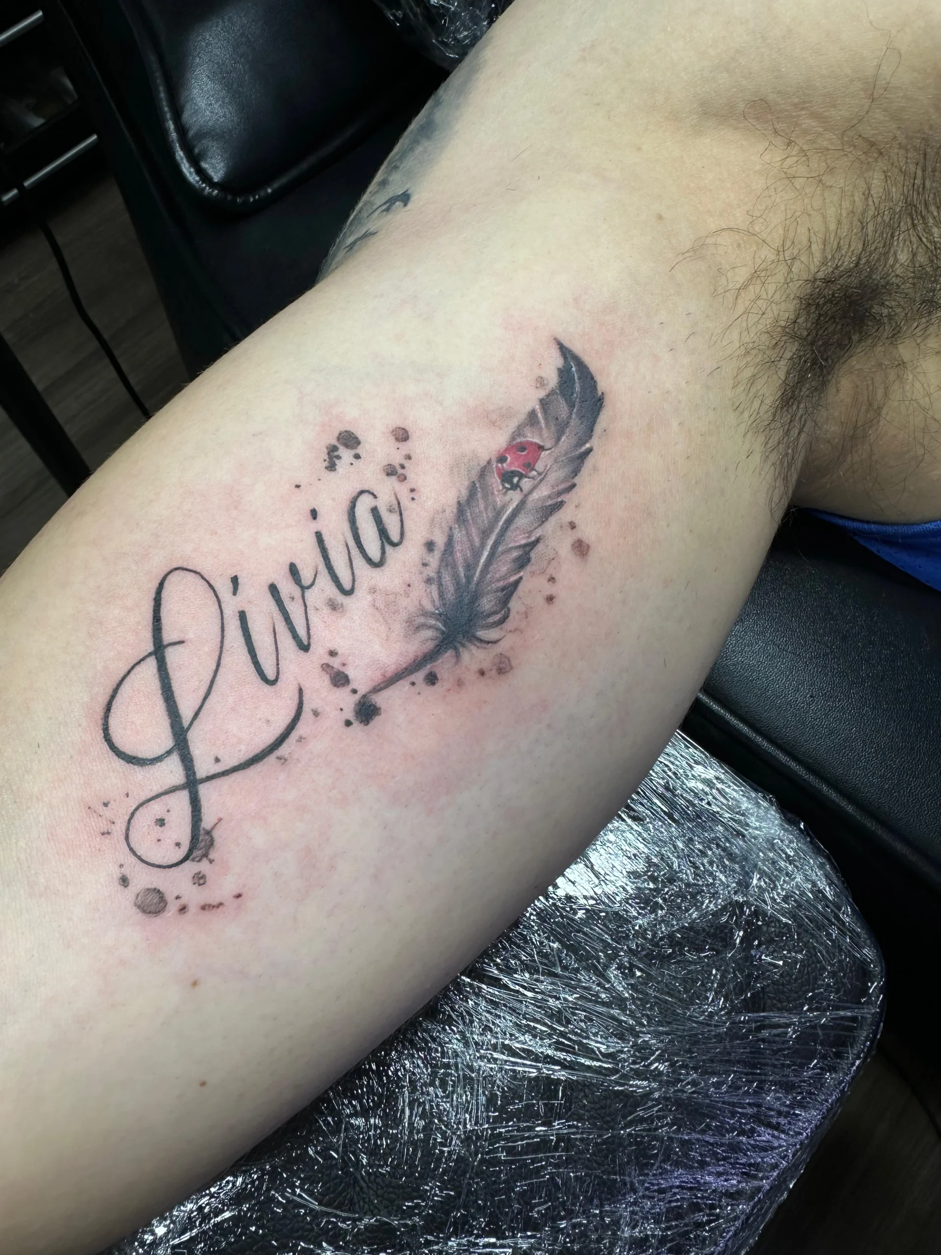 Feather and ladybug tattoo with script name custom leg ink Boca Raton FL