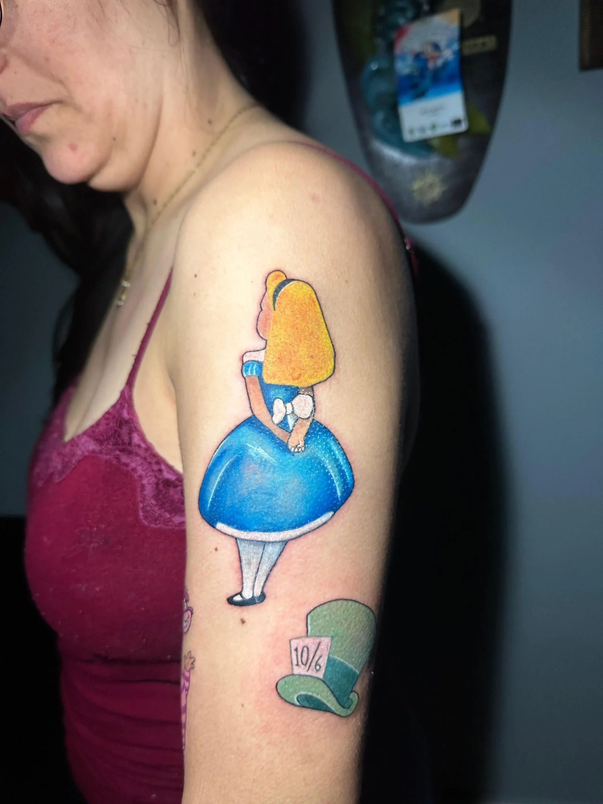 Alice in Wonderland tattoo featuring the character from behind and the Mad Hatter's hat, classic Disney ink in Boca Raton, Florida.