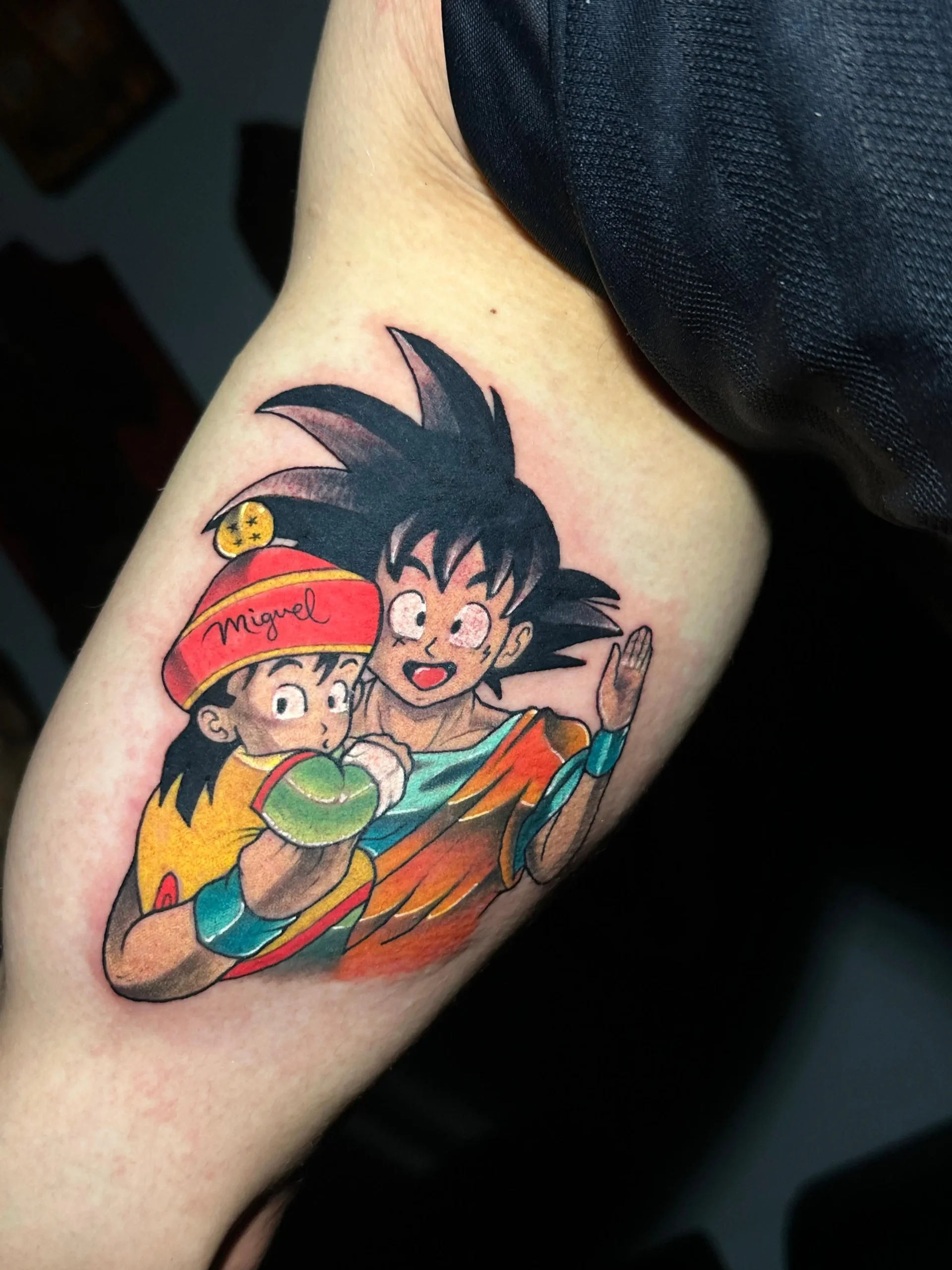 Dragon Ball Z tattoo of Goku holding baby Gohan, a colorful father-son anime tribute inked by a Boca Raton tattoo artist.