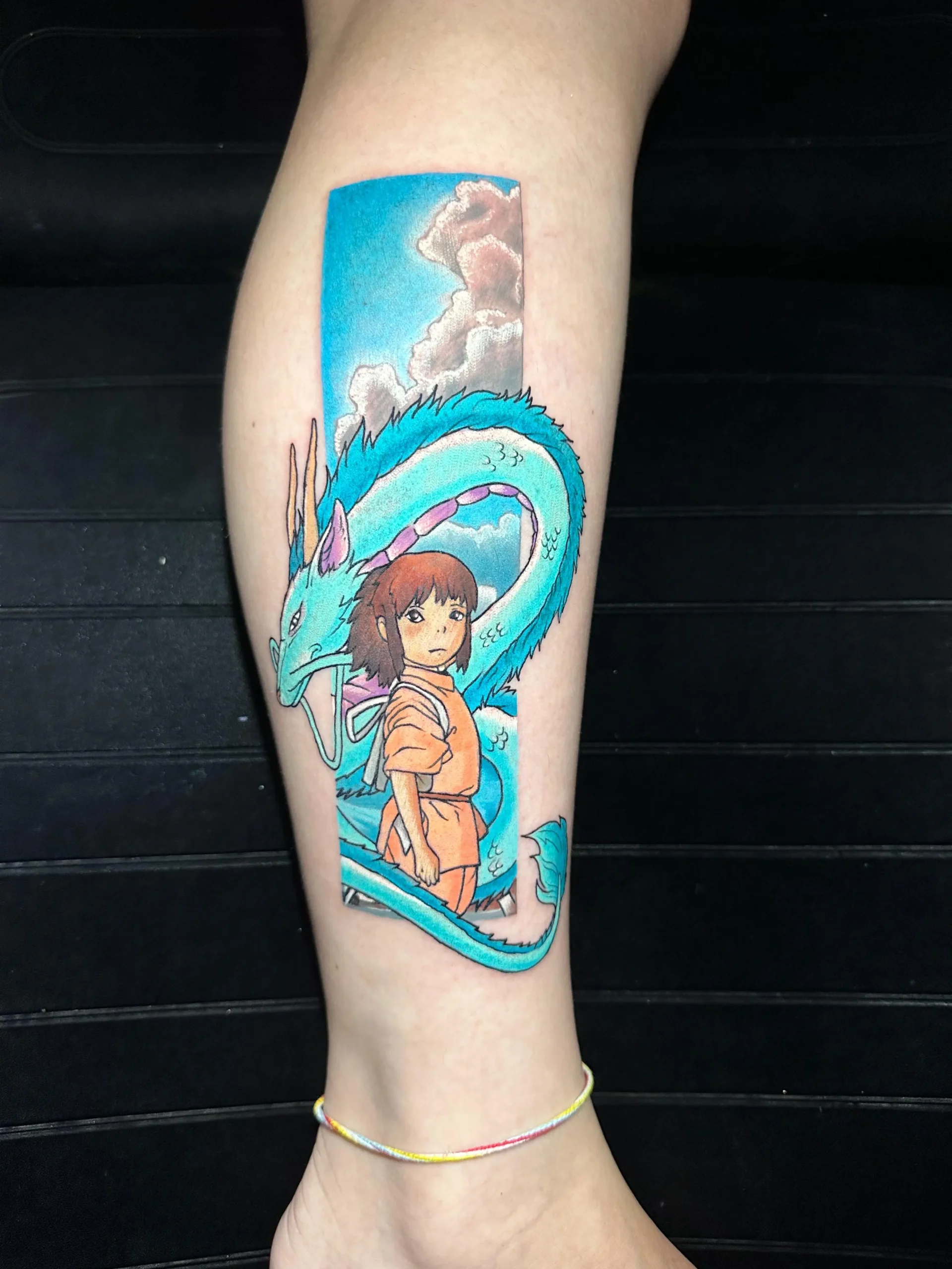 Spirited Away anime tattoo featuring Chihiro and Haku inside a rectangular panel, Studio Ghibli fan art inked in Boca Raton, Florida.