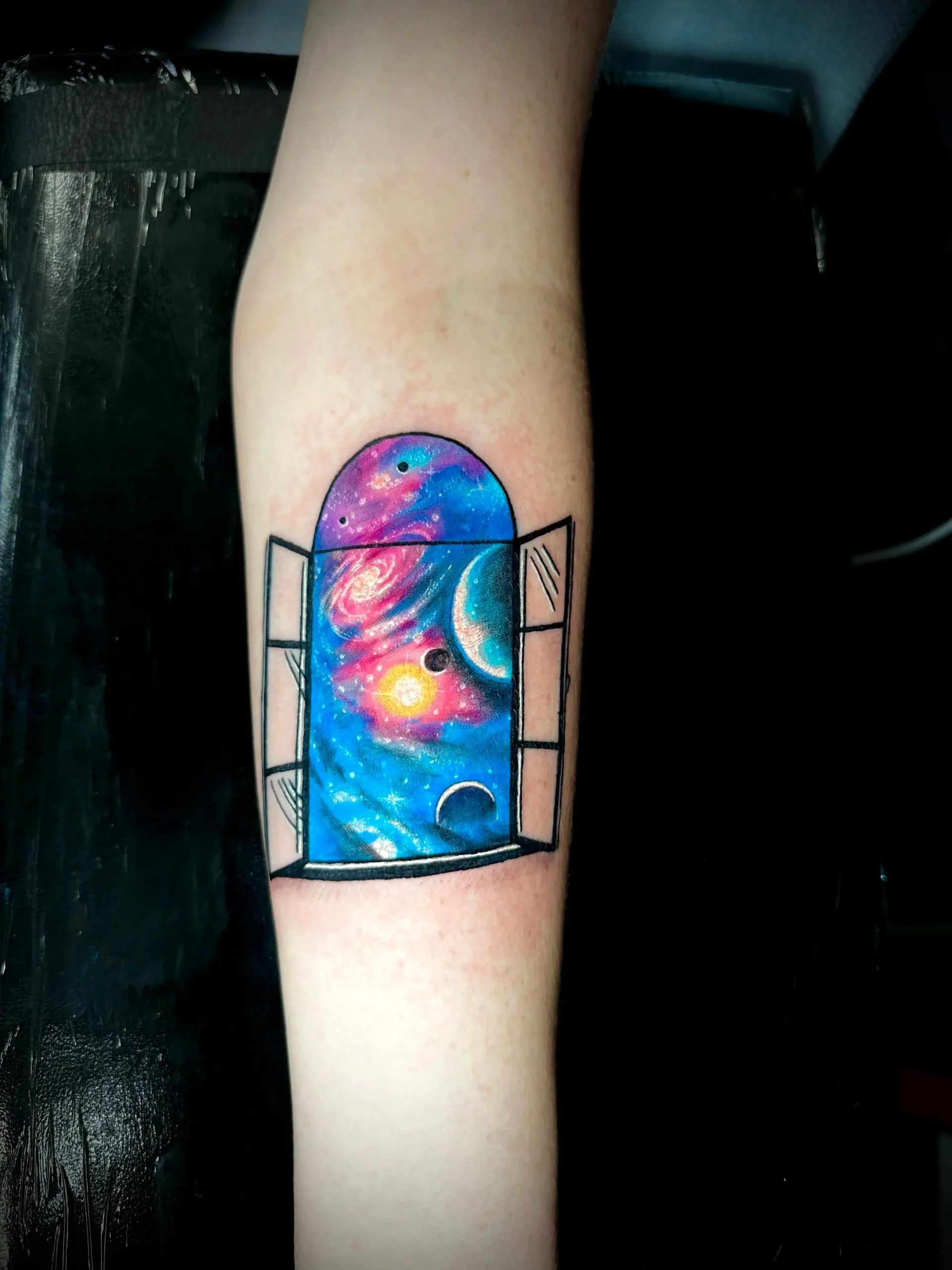 Surreal open window tattoo revealing a colorful galaxy and planets, unique cosmic art by a tattoo artist in Boca Raton, FL.