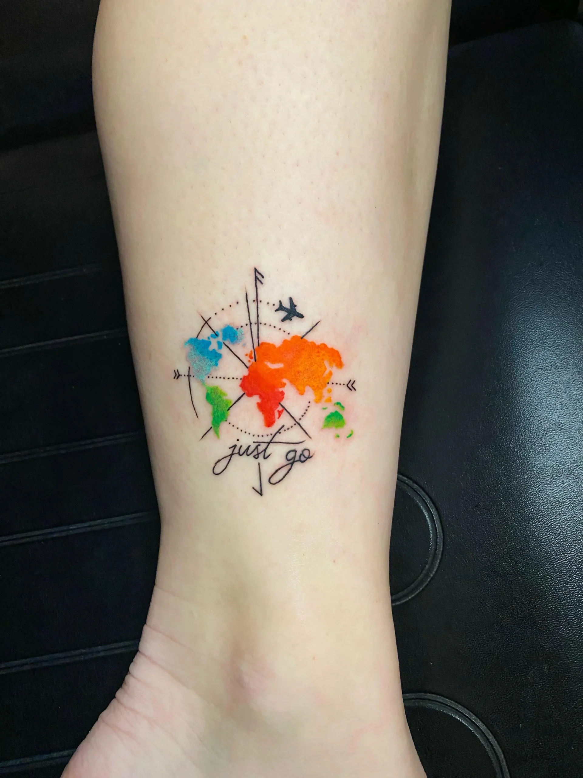 Minimalist watercolor world map tattoo with a compass and airplane, perfect travel-themed ink done at a Boca Raton tattoo studio.