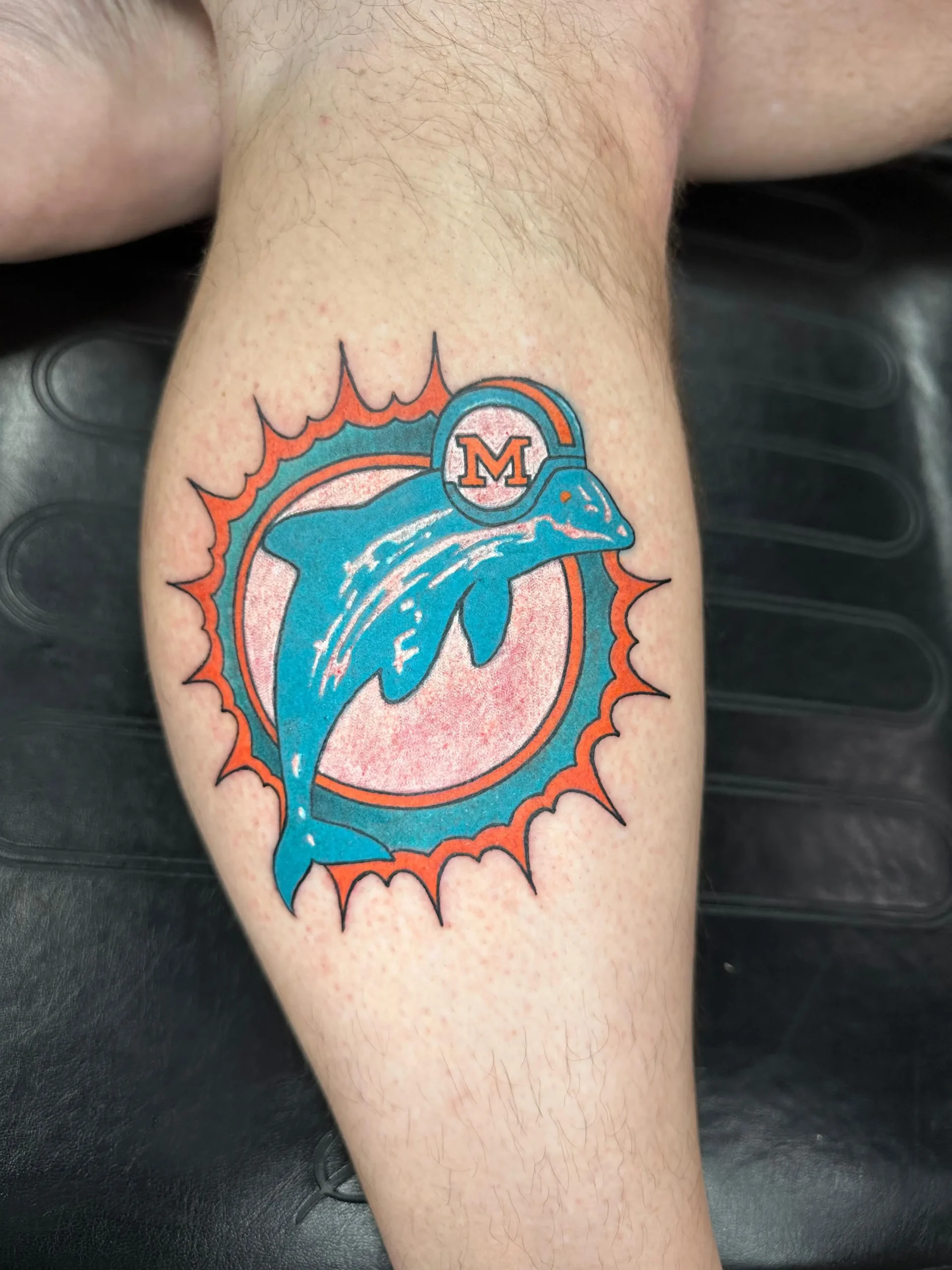 Classic Miami Dolphins logo tattoo on the calf, perfect NFL fan ink done by a professional tattoo artist in Boca Raton, South Florida.