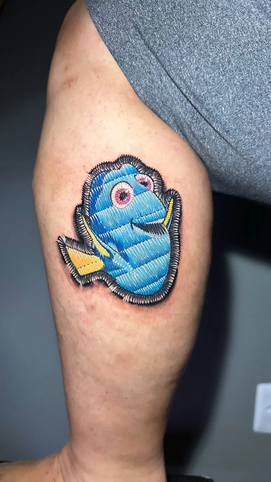 Dory from Finding Nemo tattoo in realistic embroidery patch style on the leg, cute Disney Pixar ink by a Boca Raton tattoo artist.