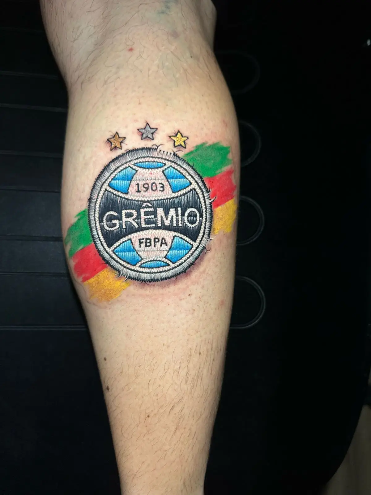 Grêmio soccer team logo tattoo in embroidery patch style on the calf, realistic stitching effect inked by a skilled artist in Boca Raton, Florida.
