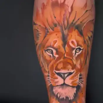 Artistic watercolor lion tattoo with vibrant orange and red tones on the calf, custom illustrative animal portrait done at a tattoo shop in Boca Raton, Florida.