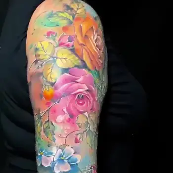 Colorful tattoo sleeve featuring detailed roses, leaves, and small flowers in shades of pink, orange, yellow, and blue, set against a black background on an upper arm. in Boca Raton, Florida