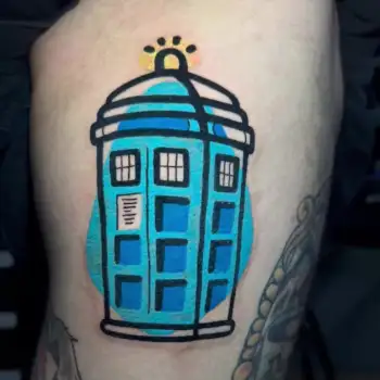 A colorful tattoo of the blue TARDIS from Doctor Who, featuring bold outlines and bright blue shading, is inked on a persons skin. in Boca Raton, Florida