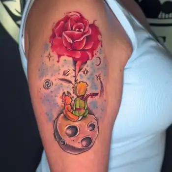 Colorful tattoo on an upper arm showing The Little Prince and a fox sitting on a small planet, looking at a large red rose with a galaxy-inspired background. in Boca Raton, Florida