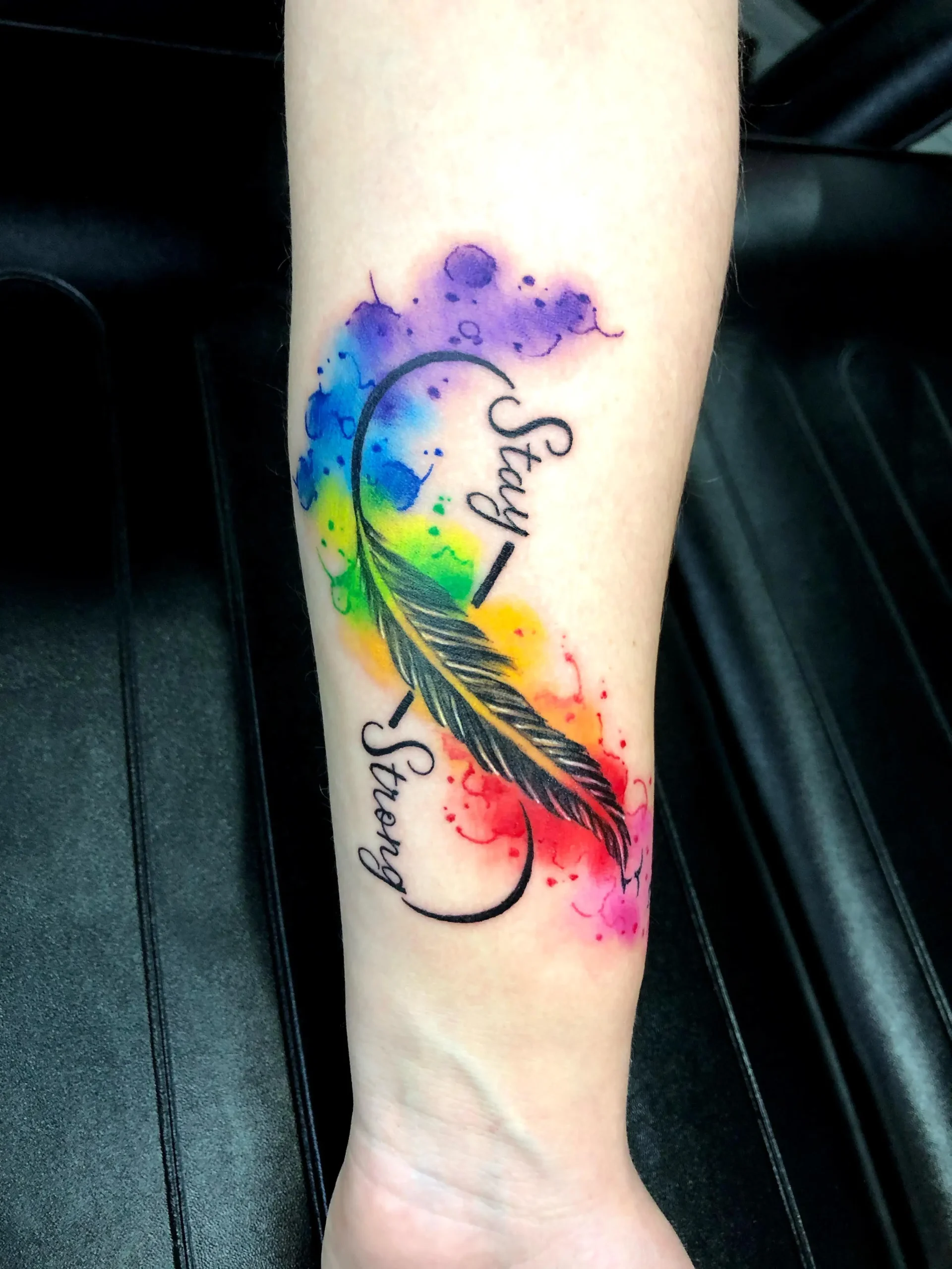 Infinity symbol feather tattoo with Stay Strong script watercolor rainbow forearm Boca Raton