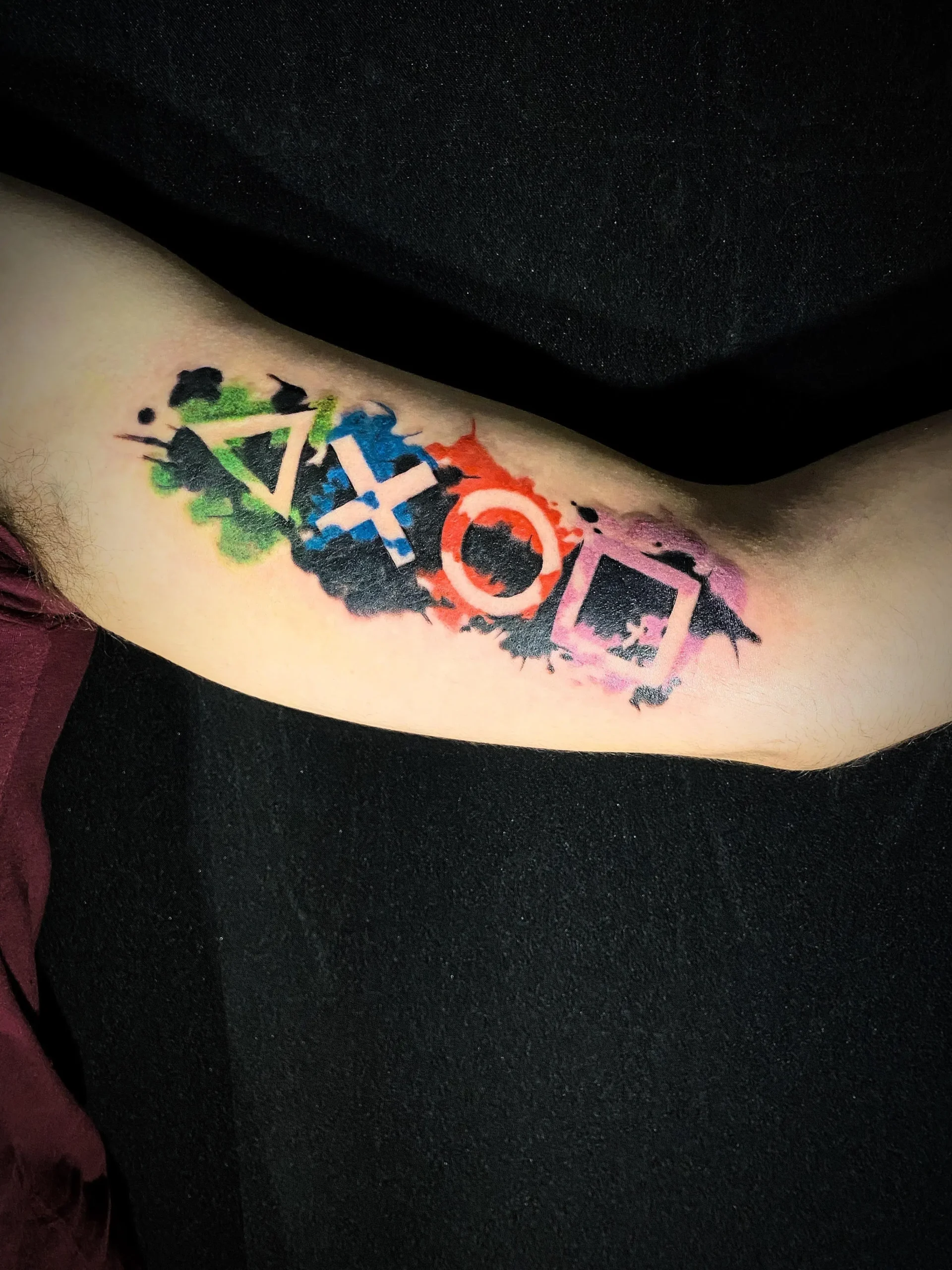 Gamer tattoo PlayStation symbols with watercolor splash on forearm Boca Raton Florida