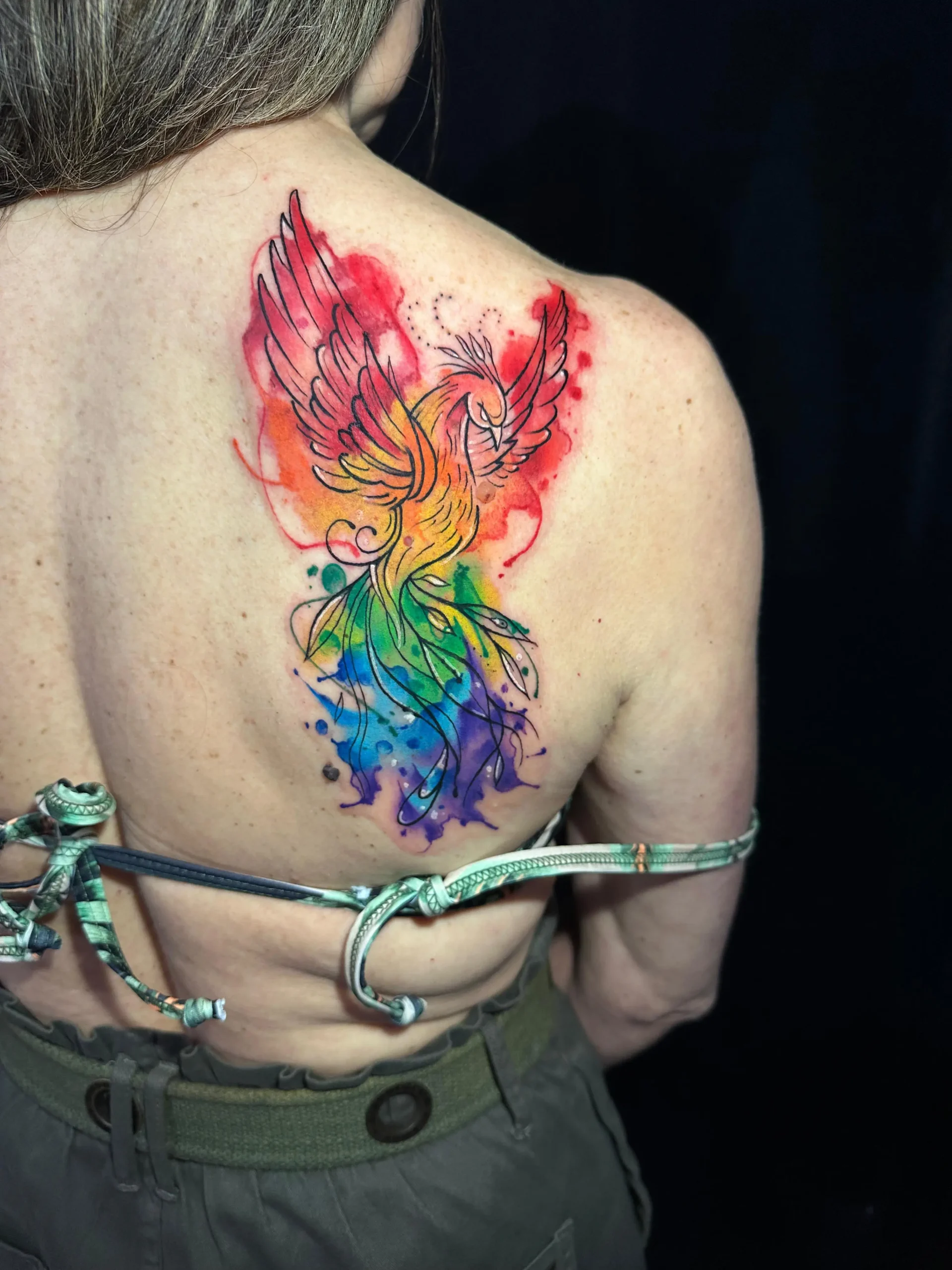 Rainbow watercolor phoenix bird tattoo on upper back rising from ashes design Boca Raton FL