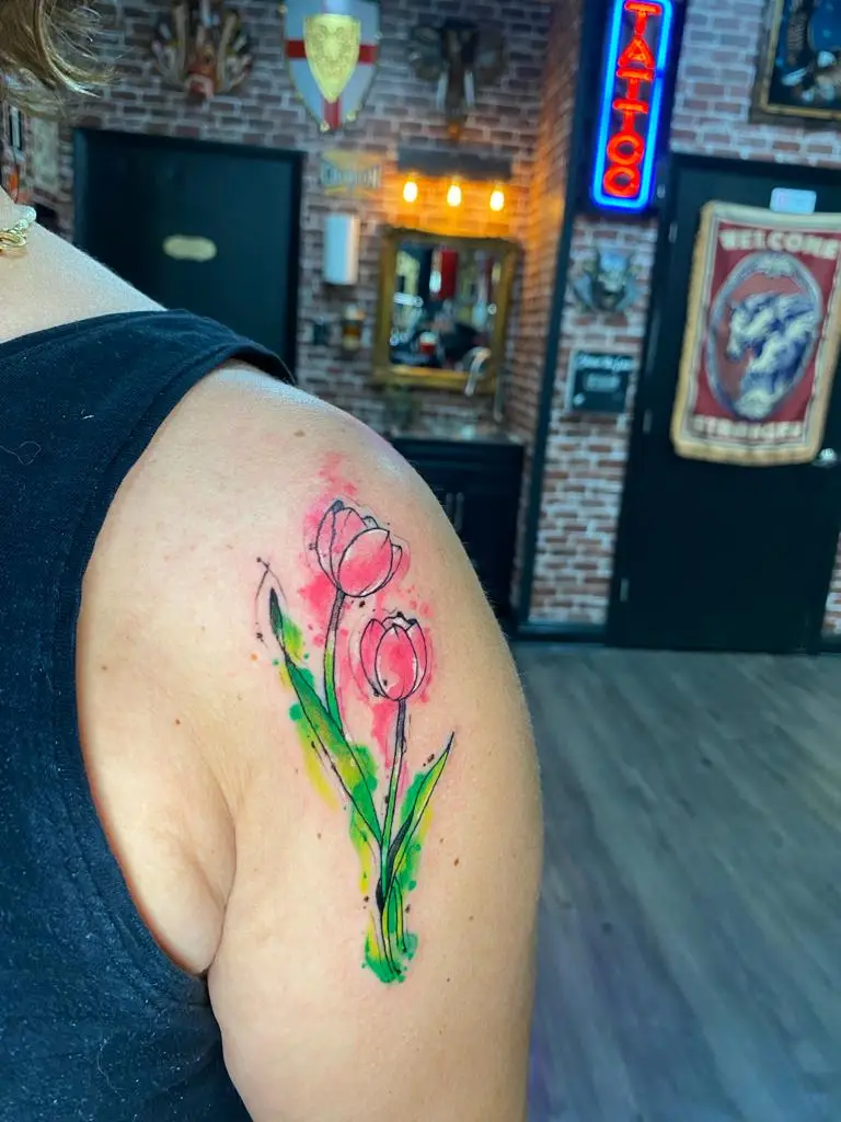 Delicate watercolor pink tulip tattoo on the shoulder with green stems, feminine floral ink done in Boca Raton, Florida.