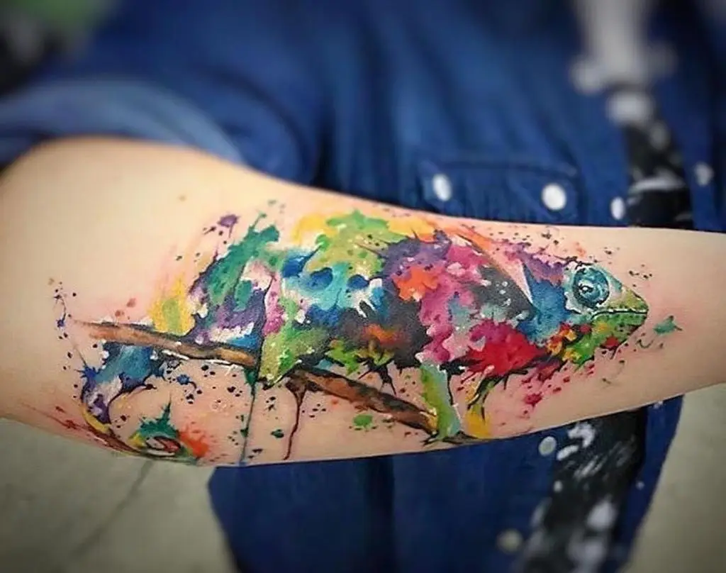 Colorful watercolor chameleon tattoo on the forearm, blending green and blue splashes, artistic reptile ink in Boca Raton, Florida.