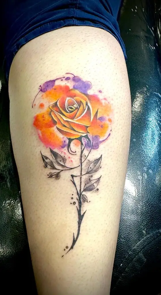 Artistic watercolor orange rose tattoo on the shoulder, sketched style floral ink done by a tattoo artist in Boca Raton, Florida.