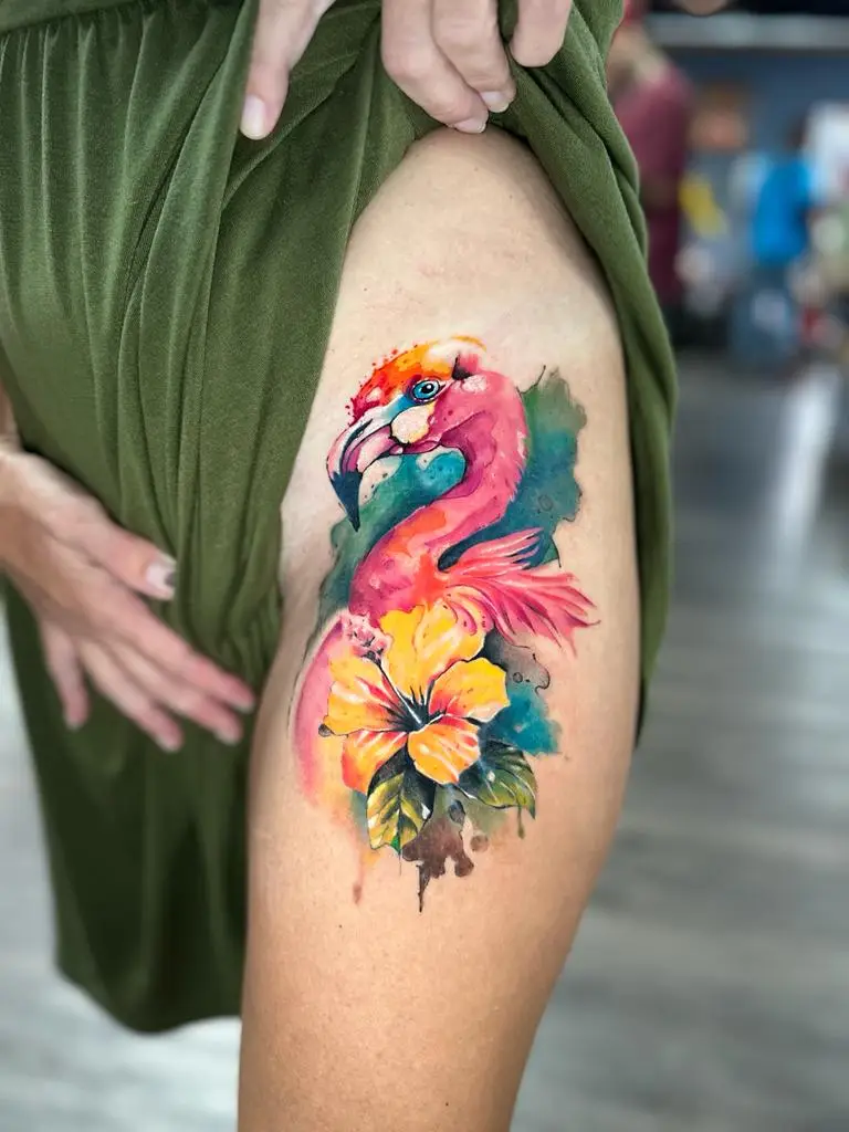 Vibrant watercolor flamingo tattoo with a yellow hibiscus flower on the thigh, tropical style ink created in Boca Raton, Florida.