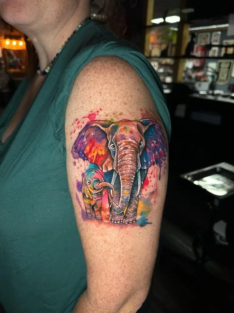 Cute mother and baby elephant tattoo in watercolor style on the arm, representing family love, inked by a specialist in Boca Raton, Florida.