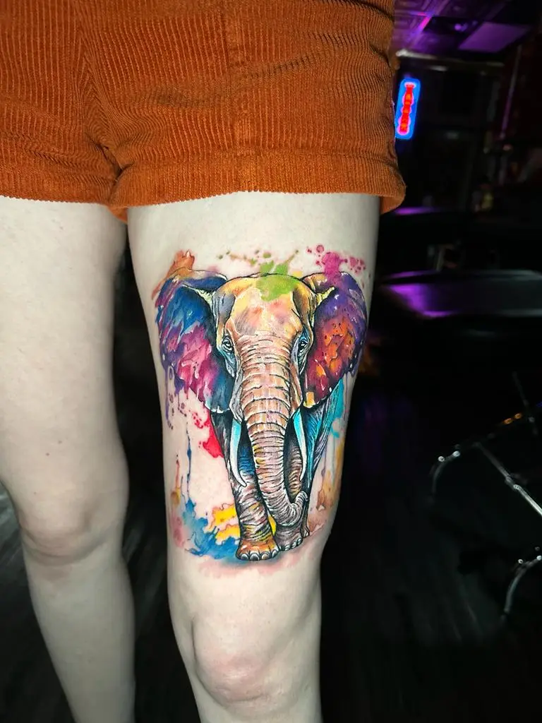 Large vibrant watercolor elephant tattoo on the thigh, colorful realistic animal portrait done by a top tattoo artist in Boca Raton, Florida.